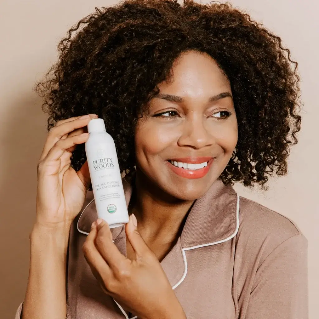 Smiling woman holding bottle of skin exfoliator