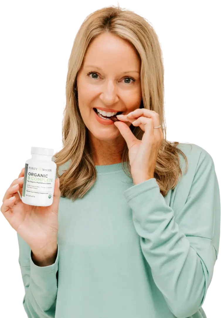 Woman holding bottle of Organic B Complete while chewing on pill.