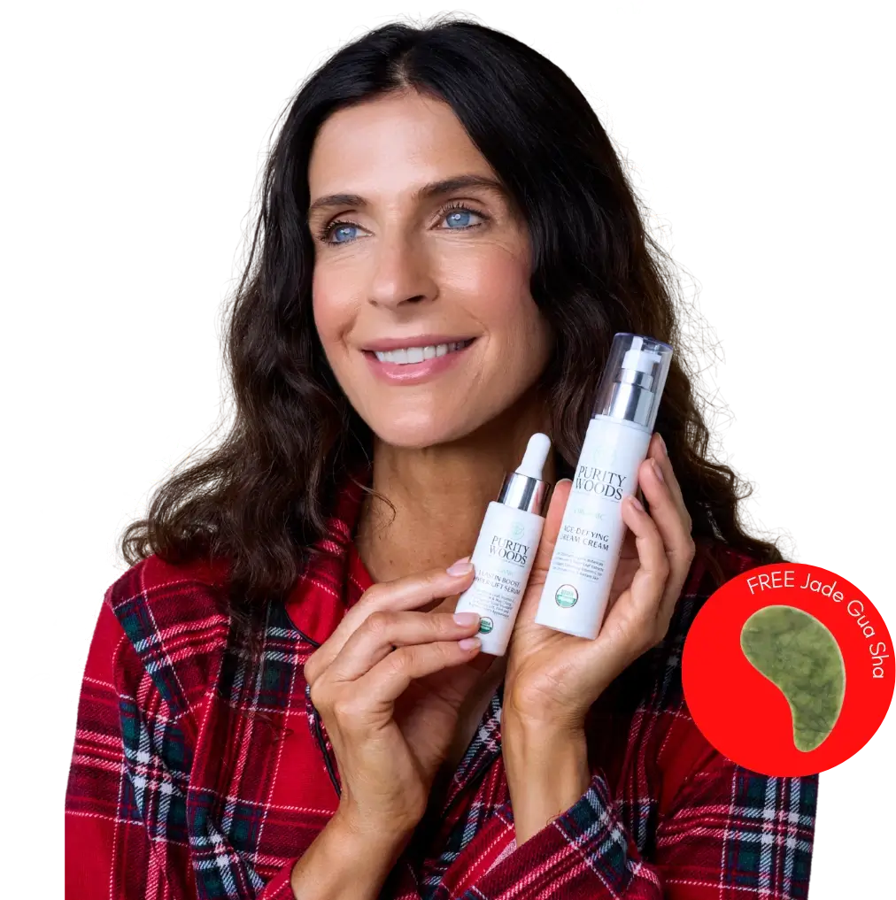 Person in a red plaid shirt smiles while holding two Purity Woods skincare products—Dream Cream and Hyper-Lift Serum—against a black background with white floral illustrations.